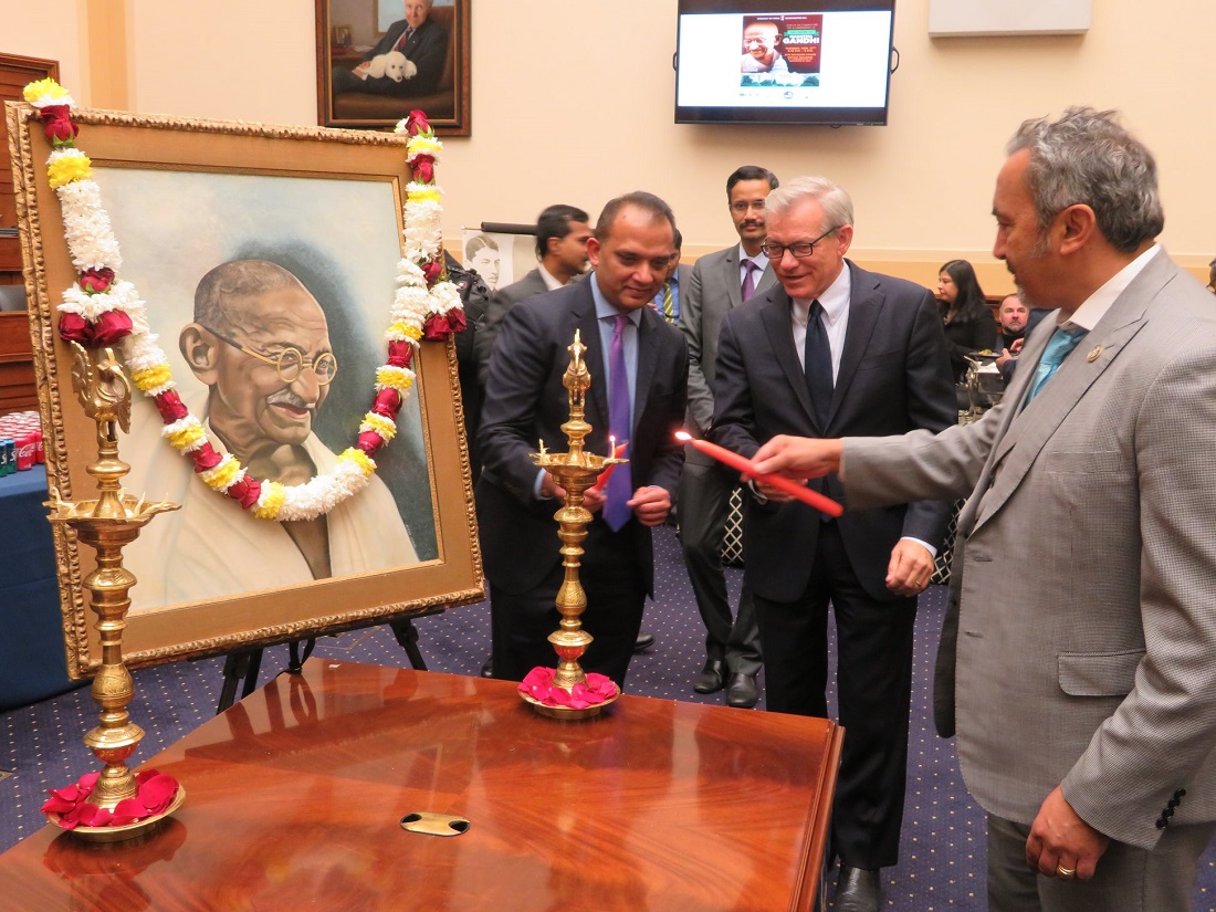 Rep. Ami Bera, D-CA, (right) lights the 'diya' (ceremonial lamp) at the launch event on Capitol Hill for the year-long celebrations of the 150th birth anniversary of Mahatma Gandhi. Seen in the center is Republican lawmaker David Schweikert of Arizona.