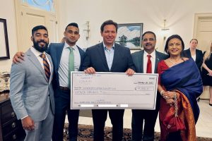 Gov. Ron DeSantis with a check presented by entrepreneur Ocala, FL, Danny Gaekwad and his wife, Manisha, for the Florida Disaster Fund during a Diwali event hosted by the governor at his official mansion. Also seen are the two children of the couple, Kunal and Karan.